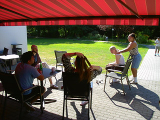 Auszubildende sitzen bei sonnigem Wetter gemeinsam auf einer Terrasse und verbringen Zeit miteinander.