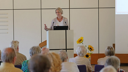 Studienleiterin Dr. Ulrike Dapp hält am Rednerpult neben einer Projektsleinwand eine Rede bei der Jubiläumsveranstaltung mit Symposium und einer Dankesveranstaltung zum 25-jährige Bestehen der LUCAS Langzeit-Kohortenstudie im Hamburger Albertinen Haus und Kirche am Albertinen Krankenhaus.