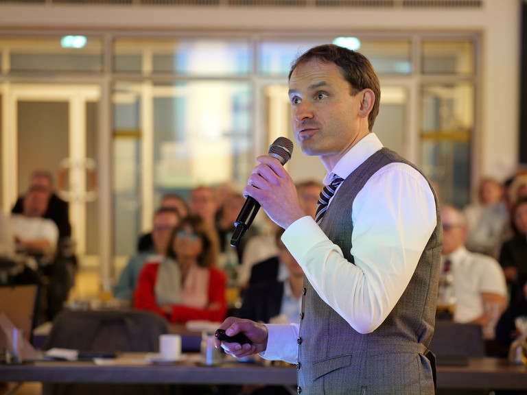 Priv.-Doz. Dr. Gödel, Chefarzt der Klinik für Geriatrie im Albertinen Zentrum für Altersmedizin im Albertinen Krankenhaus in Hamburg, spricht mit einem Mikrofon in der Hand zum Publikum bei seinem Einführungssymposium „Die Zukunft ist alt!“.