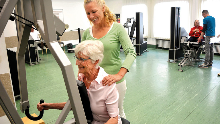 Physiotherapeutin leitet Seniorin beim Krafttraining an