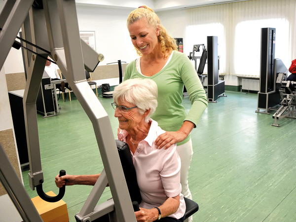 Physiotherapeutin leitet Seniorin beim Krafttraining an