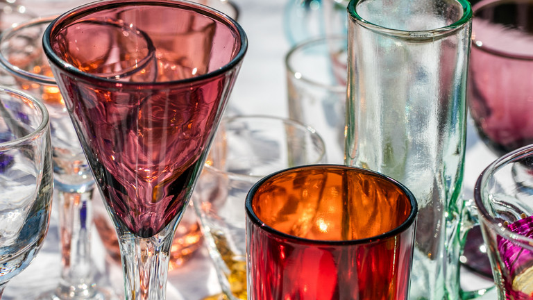 Ein Tisch mit bunten Trinkgläsern auf eine Flohmarkt. 