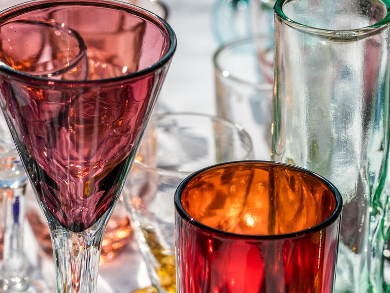Ein Tisch mit bunten Trinkgläsern auf eine Flohmarkt. 
