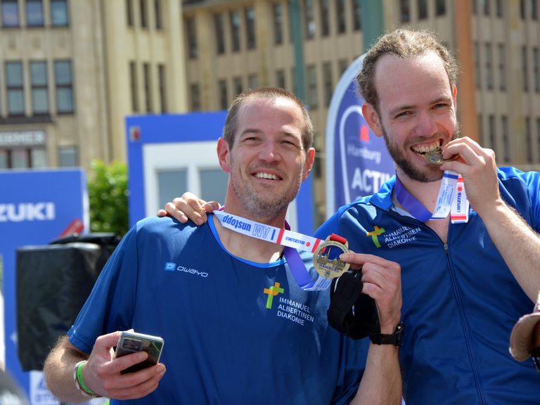 Zwei Teilnehmer mit Medaille beim Zieleinlauf World Triathlon Sprint & Relay Championships in Hamburg