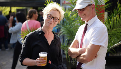 Eine Besucherin mit einem Kaltgetränk im Gespräch mit Ralf Zastrau beim Albertinen-Sommerfest für die Mitarbeitenden aus den unterschiedlichen Einrichtungen der Immanuel Albertinen Diakonie am Standort Schnelsen auf dem Platz vor der Kirche am Albertinen Krankenhaus.