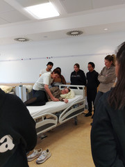 Eine Dozentin demonstriert angehenden Pflegefachpersonen eine ressourcenorientierte Lagerung nach dem Bobath-Konzept.