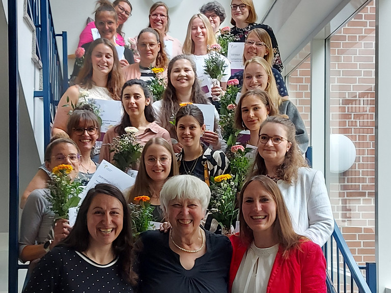 Gruppenfoto Teilnehmende mit Blumensträußen und Urkunden bei Zertifikatsübergabe DEMERGO-Kurs 2025 in der Albertinen Akademie mit den Gruppenleiterinnen sowie Gudrun Schaade, Dorothee Danke und Ann-Kathrin Blank